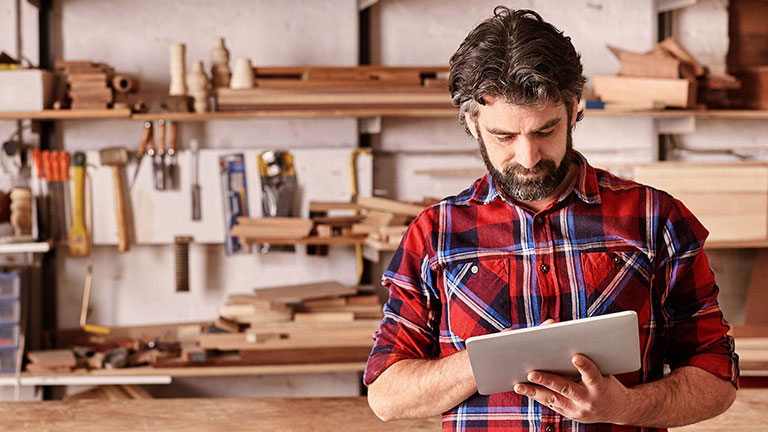 Carpenter reading about insurance coverage on tablet