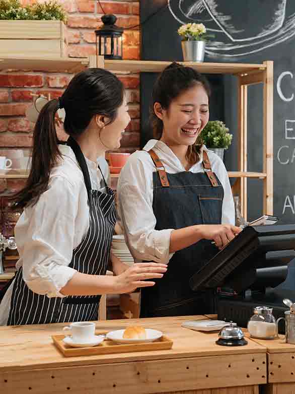 two cafe employees smiling at register