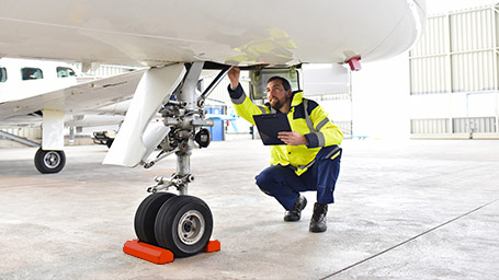Airplane mechanic inspects wheel of plane