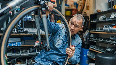 bicycle shop owner inspects bike wheel