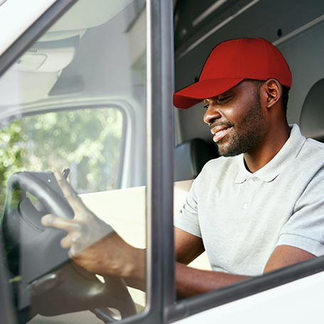 Delivery driver in parked van reviewing information on clipboard