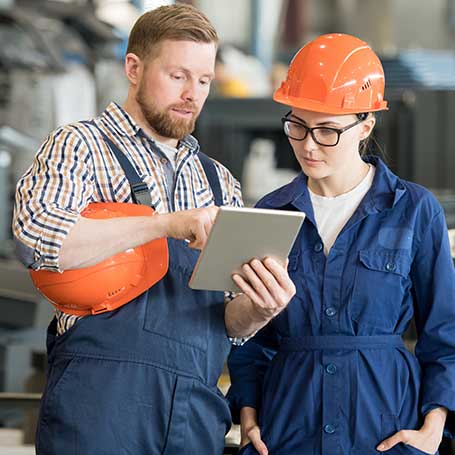 Two factory workers looking for disability insurance on tablet